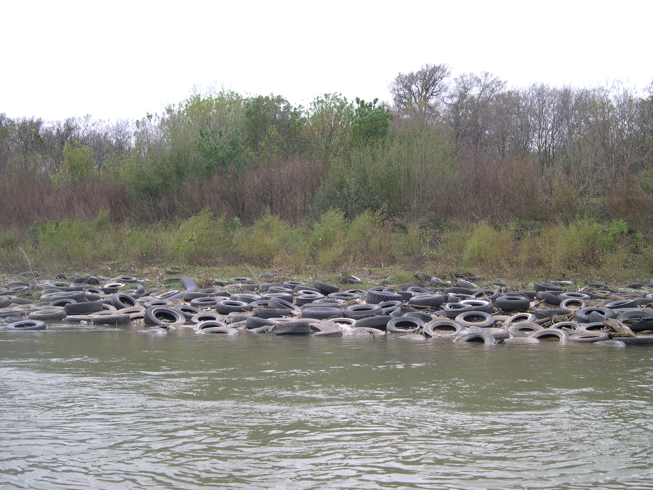 Pile of tires on the shore of the Trinity River.